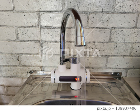 Hot water flows from the tap. Instant kitchen water heater with display and RCD Hot water flows from the tap. Instant kitchen water heater with display and RCD 138937406