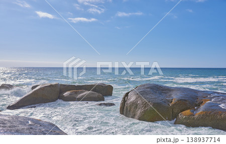 Big rocks in the ocean or sea water with a blue sky background. Beautiful landscape with a scenic view of the beach with boulders on a summer day. Relaxing scenery of the seaside or nature 138937714