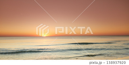 Seascape and landscape of a beautiful orange sunset on the west coast of Jutland in Loekken, Denmark. Sun setting on the horizon on an empty beach at dusk over the ocean and sea at night 138937920