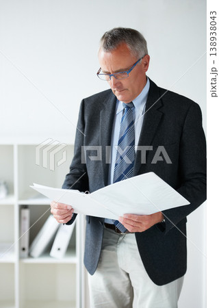 Businessman, standing amd reading documents in office or company contract, report information or confidential file. Male person, suit or paperwork thinking or corporate agreement, decision or folder Businessman, standing amd reading documents in office or company contract, report information or confidential file. Male person, suit or paperwork thinking or corporate agreement, decision or folder 138938043