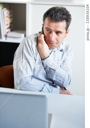 Businessman, phone and secret call in office private information, confidential or sneaky discussion. Male person, mobile or talk at laptop for inside trade, crime job or company online security break 138938104