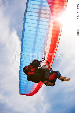People, paragliding and freedom in sky, below or extreme sport for fitness in sunshine. Coach, partnership and person on adventure, lens flare or fearless with backpack, parachute or flight in clouds People, paragliding and freedom in sky, below or extreme sport for fitness in sunshine. Coach, partnership and person on adventure, lens flare or fearless with backpack, parachute or flight in clouds 138938369