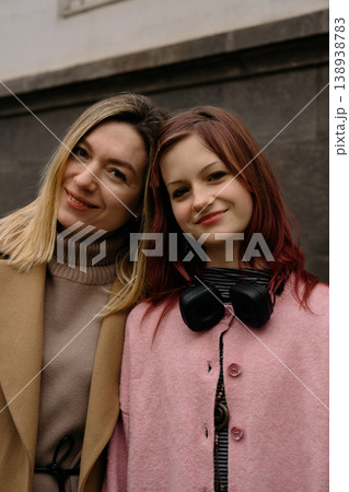 Mother and daughter smiling together in the city, enjoying a moment outdoors in cool weather 138938783