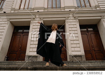 Girl wearing a black cape standing on steps of a building during daytime Girl wearing a black cape standing on steps of a building during daytime 138938912