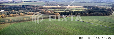 Green landscape of a countryside with autumn colors. Aerial view of a sustainable, cultivated farmland or flat land with grass surrounded by a traditional farm house and lots of forest trees Green landscape of a countryside with autumn colors. Aerial view of a sustainable, cultivated farmland or flat land with grass surrounded by a traditional farm house and lots of forest trees 138938950