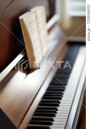 The piano. A vintage grand piano with a book of sheet music for education. An antique and classic keyboard is used to develop skills. A classical wooden musical instrument for practising music. The piano. A vintage grand piano with a book of sheet music for education. An antique and classic keyboard is used to develop skills. A classical wooden musical instrument for practising music. 138938952