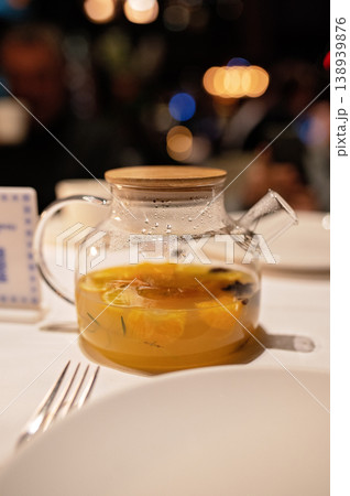 Glass teapot with citrus fruit infusion on table in restaurant setting with blurred background Glass teapot with citrus fruit infusion on table in restaurant setting with blurred background 138939876