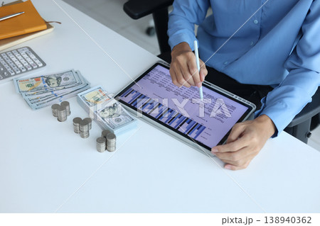 Close-up hand using digital tablet for tracking or analyzing financial data for budgeting and planning. 138940362