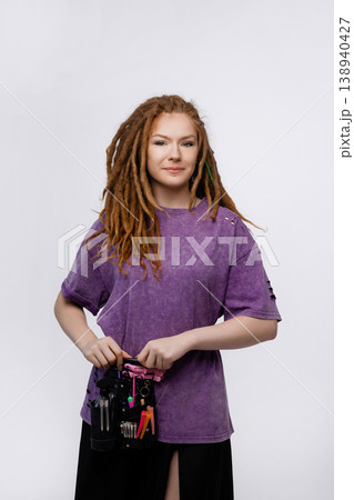 Smiling female braider with dreadlocks and tools belt isolated on white background 138940427