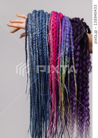 Female hand holding colorful braid extensions isolated on white background 138940433