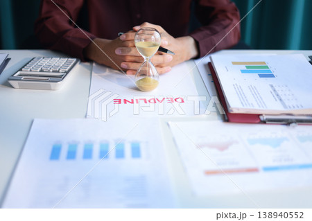 Businessman working on office desk with deadline document and running sand clock. Time management concept. Businessman working on office desk with deadline document and running sand clock. Time management concept. 138940552