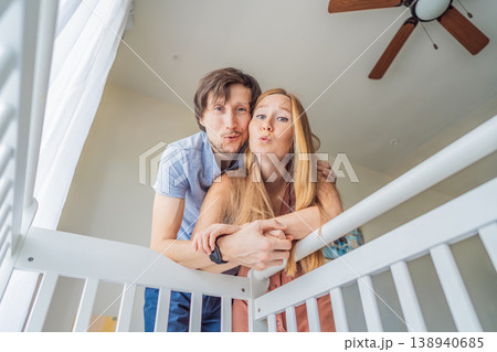 Parents looking into baby crib from infant point of view. Mother and father smiling down at newborn with love and care. Family bonding, parenthood, childhood memory and emotional connection concept 138940685