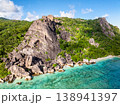 Imposing rocky cliffs rise above lush greenery, with turquoise waters at the base. Seychelles, La Digue. 138941397