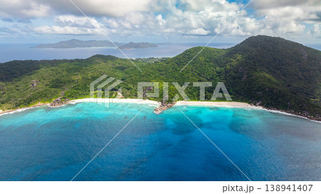 Turquoise waters meeting tropical green hills on a sunny coastline. La Digue, Seychelles. Turquoise waters meeting tropical green hills on a sunny coastline. La Digue, Seychelles. 138941407
