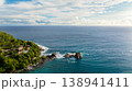 A dense green forest covering a rocky coastline, with clear turquoise waters. Seychelles, Mahe. 138941411