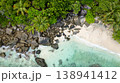 Clear emerald waters gently lapping against a sandy beach surrounded by lush greenery. Butzel Beach. Seychelles, Mahe. 138941412