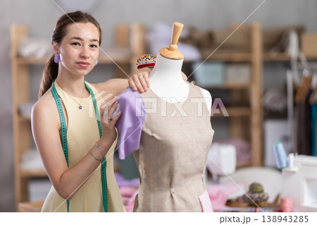Woman seamstress adjusts clothes on mannequin Woman seamstress adjusts clothes on mannequin 138943285