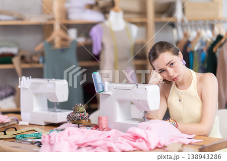 Tired seamstress working at sewing machine Tired seamstress working at sewing machine 138943286