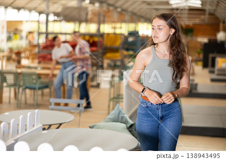Girl exploring with interest furniture and garden supplies at store Girl exploring with interest furniture and garden supplies at store 138943495