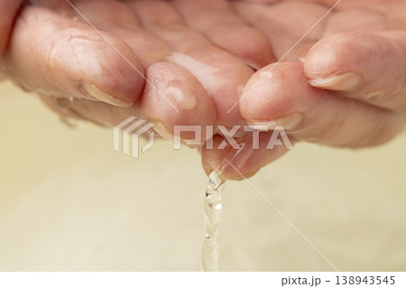 両手で洗面器の水をすくう 138943545