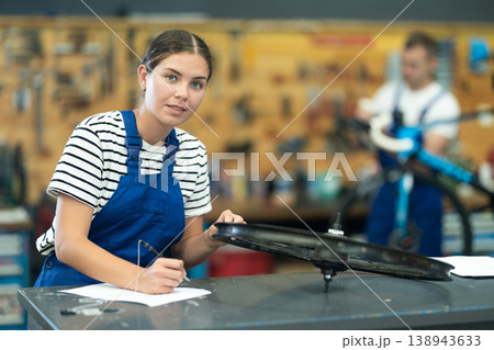 Female bicycle repair service worker signing document Female bicycle repair service worker signing document 138943633