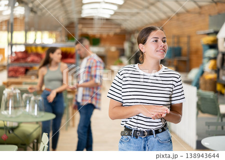 Girl exploring with interest furniture and garden supplies at store Girl exploring with interest furniture and garden supplies at store 138943644