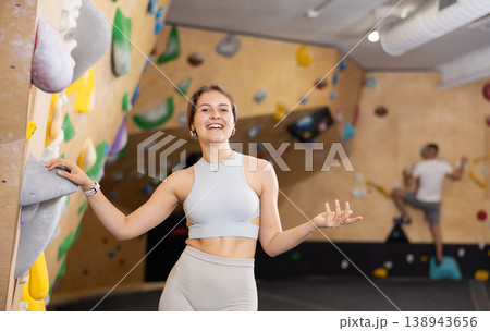 Smiling female climbing instructor showing indoor bouldering wall Smiling female climbing instructor showing indoor bouldering wall 138943656