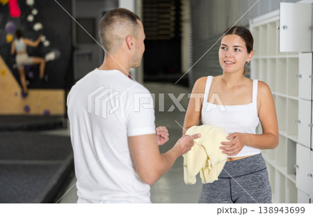 Smiling girl talking with friend by storage lockers in bouldering gym Smiling girl talking with friend by storage lockers in bouldering gym 138943699