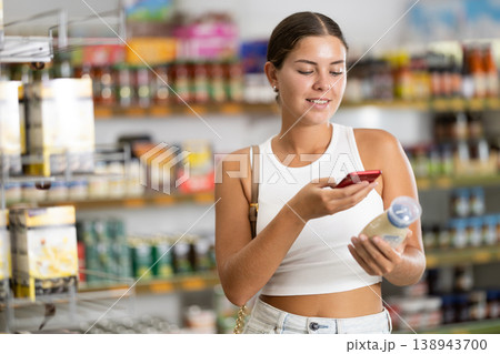 Girl scanning barcode or qr code with smartphone on mayonnaise label in supermarket 138943700