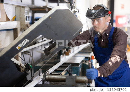 Workman cutting PVC profile on industrial machine in production workshop 138943702