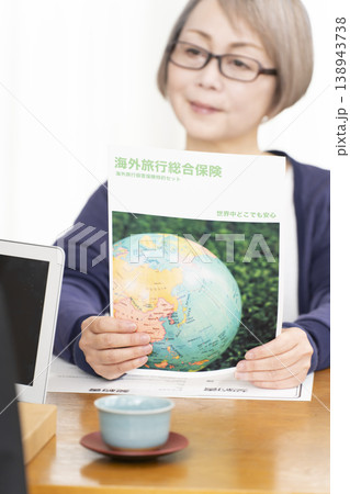 海外旅行保険の契約書に署名捺印するシニア女性の手元 海外旅行保険の契約書に署名捺印するシニア女性の手元 138943738