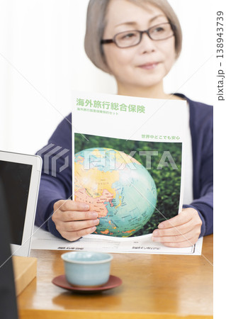 海外旅行保険の契約書に署名捺印するシニア女性の手元 138943739