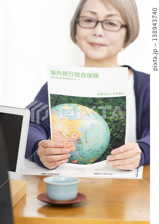 海外旅行保険の契約書に署名捺印するシニア女性の手元 海外旅行保険の契約書に署名捺印するシニア女性の手元 138943740