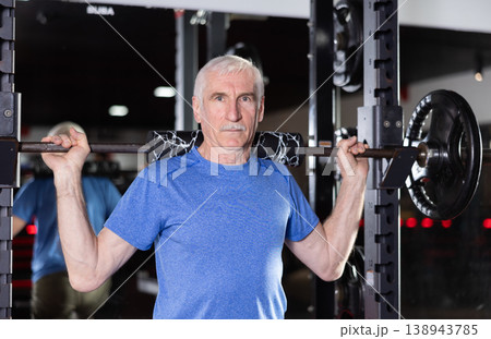 Active man during exercises to strengthen muscles of hands and body using barbell and extra weight 138943785