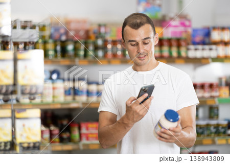 Male shopper scanning barcode or qr code with smartphone on mayonnaise label Male shopper scanning barcode or qr code with smartphone on mayonnaise label 138943809