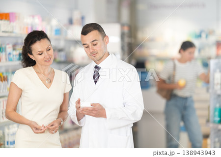Man pharmacist helps woman buyer to decide on choice an medicine 138943943