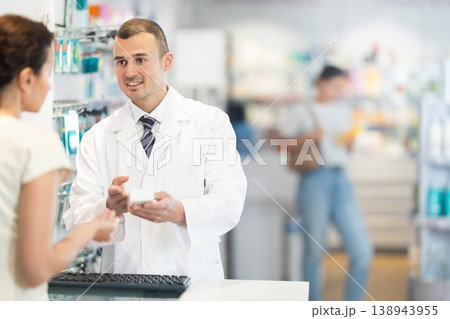 Male pharmacist speaking to woman customer buying medical preparation in drugstore 138943955