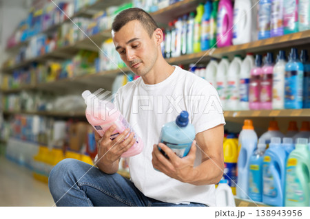 Man customer in store chooses package of laundry detergent Man customer in store chooses package of laundry detergent 138943956