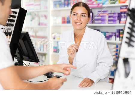 Young female pharmacist serving client buying medicament in drugstore Young female pharmacist serving client buying medicament in drugstore 138943994