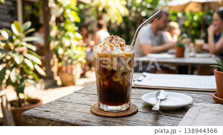 夏のカフェテラスで楽しむアイスコーヒー、クリームトッピングとメタルストロー 138944366