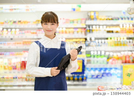 笑顔でタブレットを持つ女性店員 笑顔でタブレットを持つ女性店員 138944403