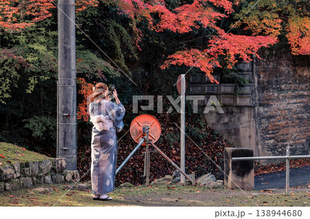 Woman in Blue Kimono Walking Among Colorful Foliage Nov 26 2025 138944680