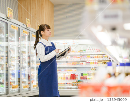 スーパーの通路でタブレットを確認する女性店員 138945009