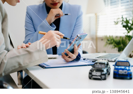 Car insurance consultation using smartphone and documents. Advisor and customer reviewing digital insurance service, auto policy, finance, technology 138945641
