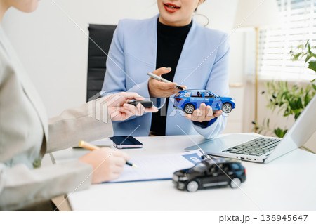 Car saleswoman handing over car key to customer at showroom. Vehicle purchase, auto finance, contract signing and successful car sales business concept. 138945647