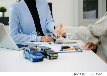 Car saleswoman handing over car key to customer at showroom. Vehicle purchase, auto finance, contract signing and successful car sales business concept. Car saleswoman handing over car key to customer at showroom. Vehicle purchase, auto finance, contract signing and successful car sales business concept. 138945648