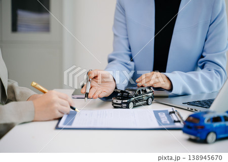 Car insurance contract signing with financial advisor. Customer reviewing agreement with car model on desk, representing auto insurance, finance, loan 138945670