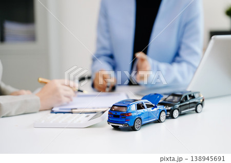 Professionals reviewing a car accident claim with model vehicles, illustrating auto insurance, risk assessment, and financial consultation in office Professionals reviewing a car accident claim with model vehicles, illustrating auto insurance, risk assessment, and financial consultation in office 138945691