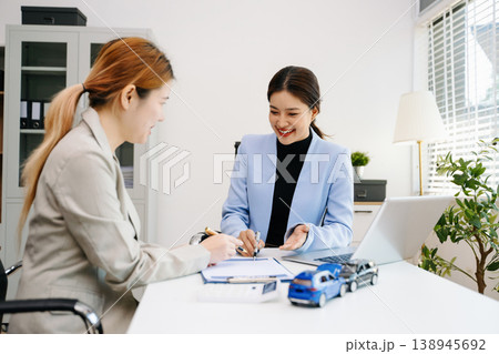 Professionals reviewing a car accident claim with model vehicles, illustrating auto insurance, risk assessment, and financial consultation in office 138945692