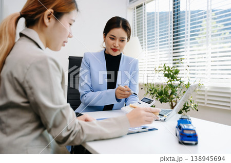 Professionals reviewing a car accident claim with model vehicles, illustrating auto insurance, risk assessment, and financial consultation in office 138945694